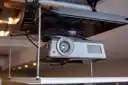 Thumbnail of A projector mounted to a motorised mechanism lowered from the ceiling