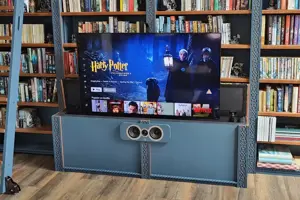 A TV raised out of a cabinet with in a bespoke, custom built library